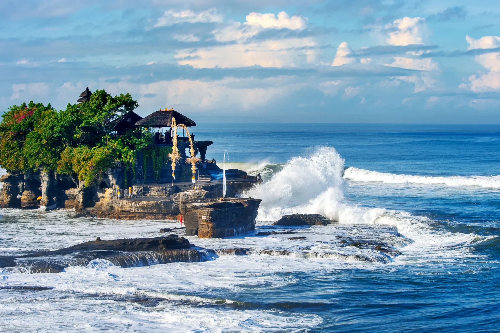 Tanah Lot Temple in Bali standing on a rocky island with ocean waves during daylight